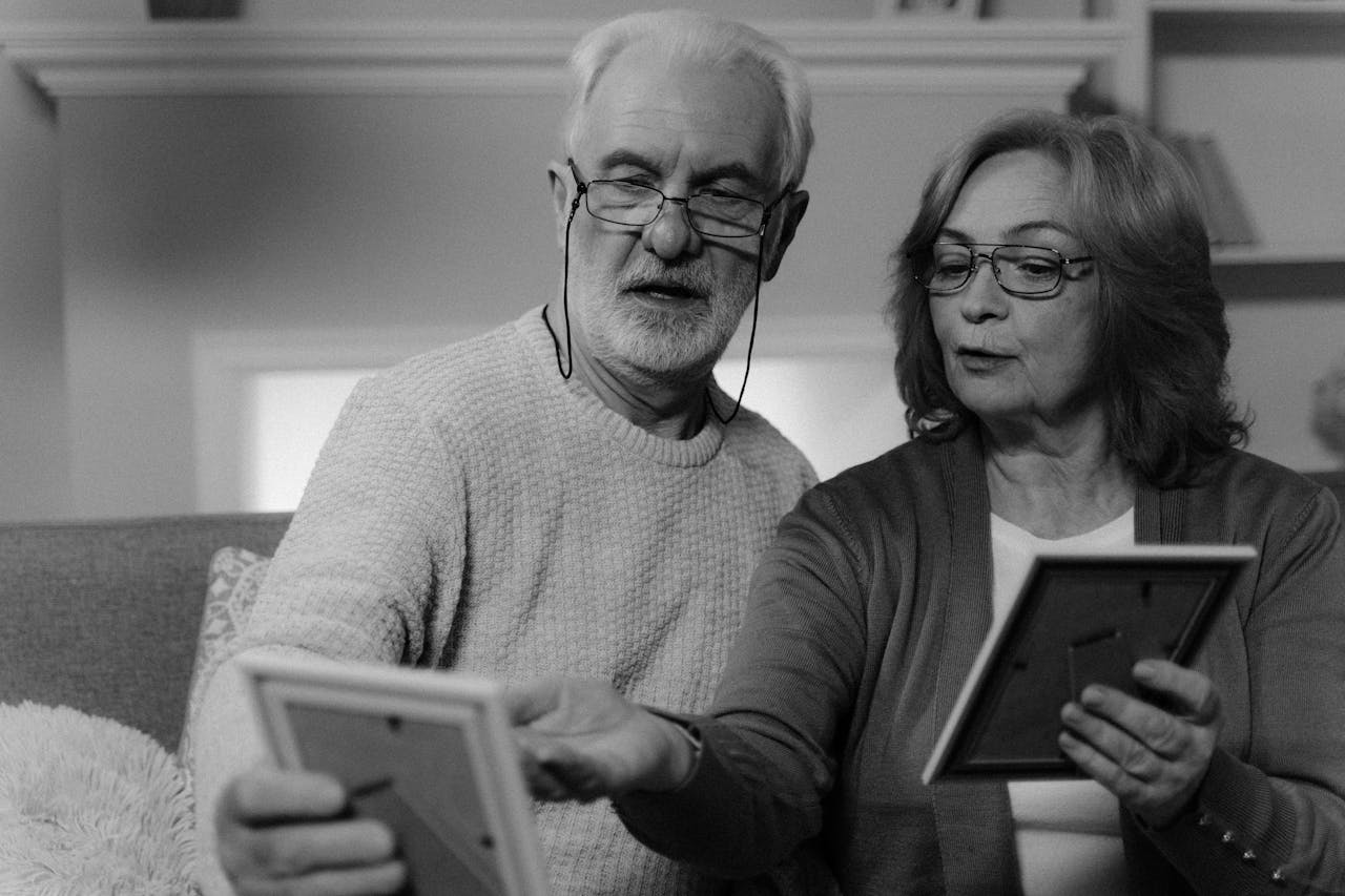 Senior couple cherishing old photographs at home, sharing memories.